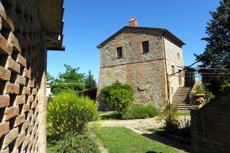 Ein historisches Gebäude aus Stein, umgeben von Grün, das eine ruhige und entspannende Umgebung schafft.