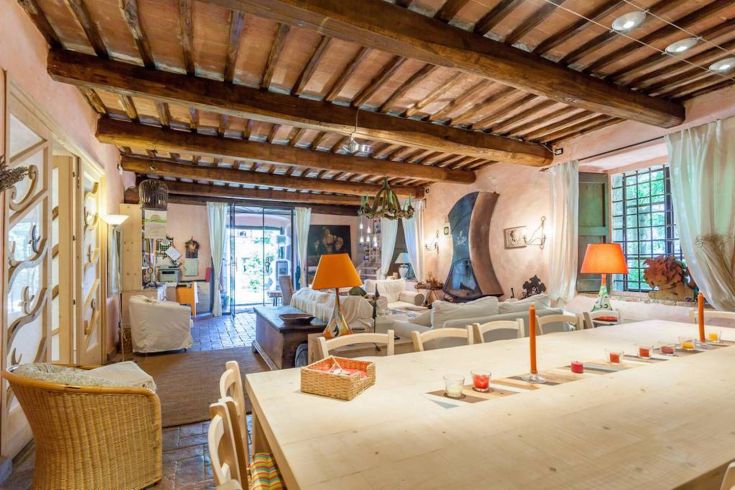 Ein gemütliches Interieur mit sichtbaren Balken und einem großen Tisch in einer naturnahen Umgebung.