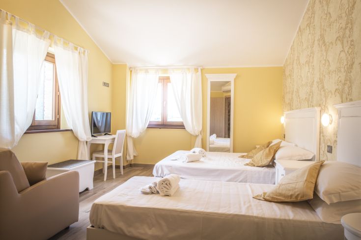 Camera ben illuminata con arredamento semplice, letti singoli e panorama sulla campagna umbra.