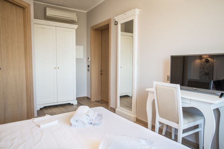 Camera accogliente con arredi contemporanei, specchio e panorama sulla natura circostante.