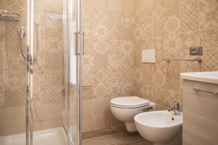 Bagno funzionale con doccia e piastrelle decorative, dall'atmosfera contemporanea.