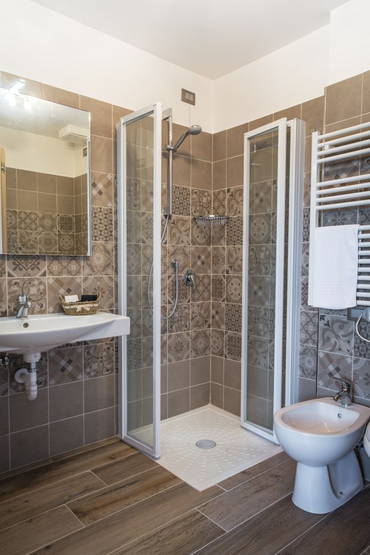 Bagno semplice con piastrelle di ceramica, doccia e lavabo, in un contesto funzionale e contemporaneo.