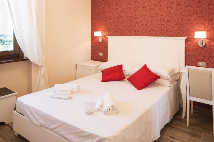 Camera semplice con letti bianchi e cuscini rossi, in un ambiente gradevole e tranquillo.