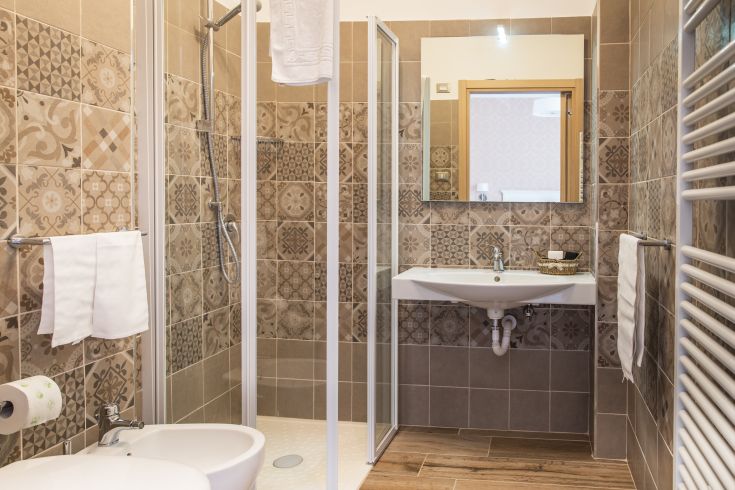Bagno moderno caratterizzato da piastrelle decorate e una doccia funzionale. Atmosfera tranquilla e contemporanea.
