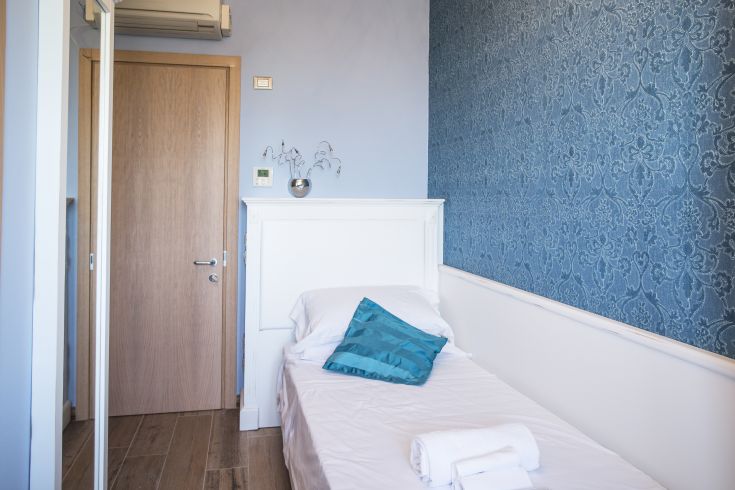 Camera tranquilla dai toni blu, arredata in modo semplice per un soggiorno confortevole.