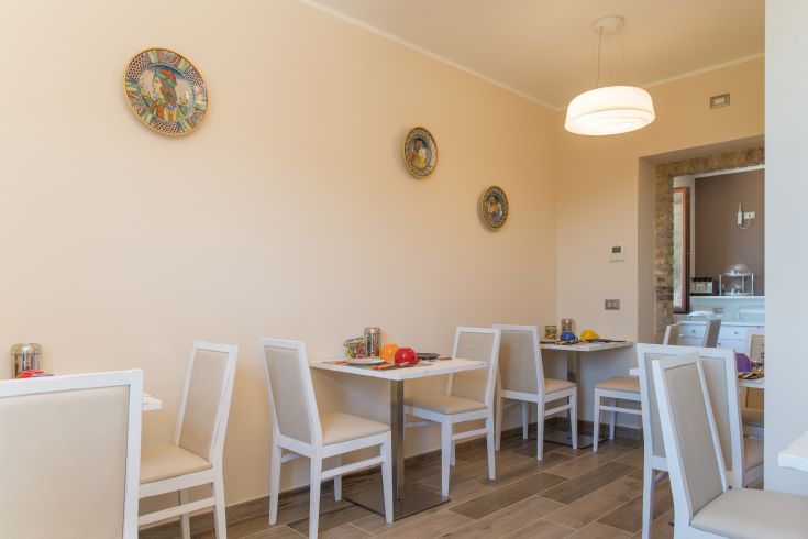 Un ambiente semplice e luminoso con tavoli bianchi e decorazioni sobrie.