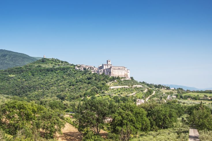 Panorama su Assisi con la Basilica di San Francesco, circondata dal verde della campagna umbra.