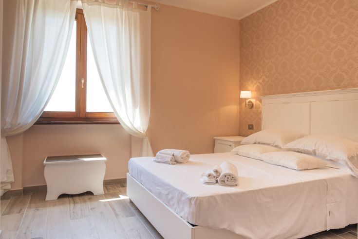 Camera semplice con letto matrimoniale, arredi pratici e buona illuminazione naturale.