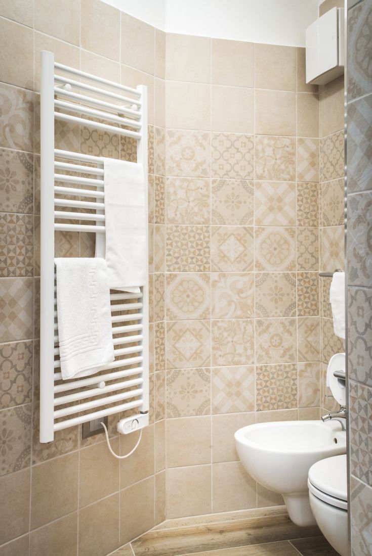 Bagno moderno con piastrelle decorate e termosifone bianco. Spazio semplice e confortevole.