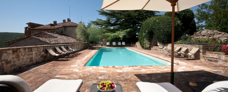 Un castello medievale immerso nella tranquilla campagna umbra, circondato da natura e con piscina.