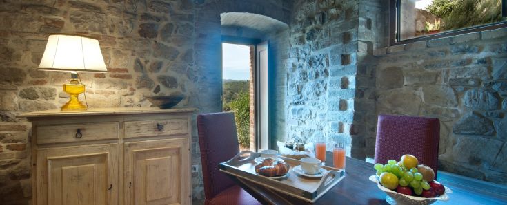 Un ambiente tranquillo con pareti in pietra e tavoli all'aperto, perfetto per una colazione in campagna.