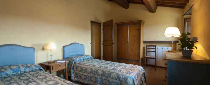 Una stanza semplice con due letti, arredata con colori caldi. Ambiente tranquillo e riposante.