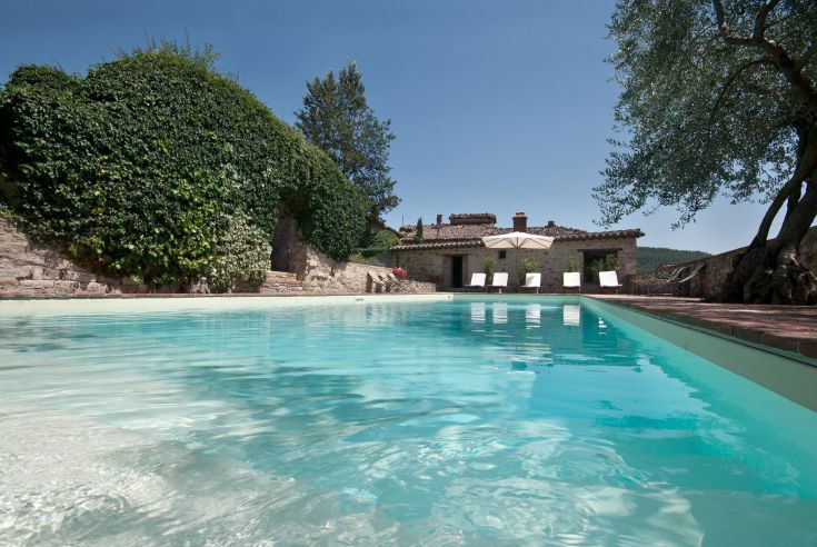 Un luogo tranquillo immerso nella natura, con piscina e panorama su un antico castello.