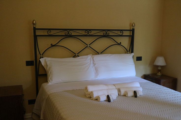 Chambre accueillante avec un lit double, du linge propre et des détails rustiques simples.