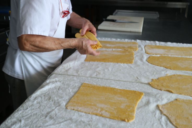 Un chef étale des pâtes fraîches à la main, mettant en valeur la tradition culinaire locale.