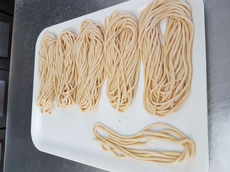 Une image de pâtes fraîches faites maison en différentes formes, prêtes à être cuites.