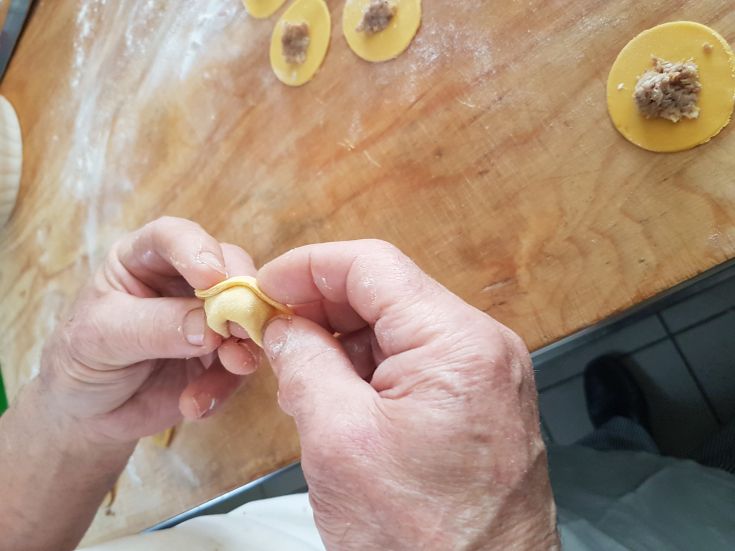 Préparation de raviolis frais sur une table en bois, avec des compositions de pâte et de farce visibles.