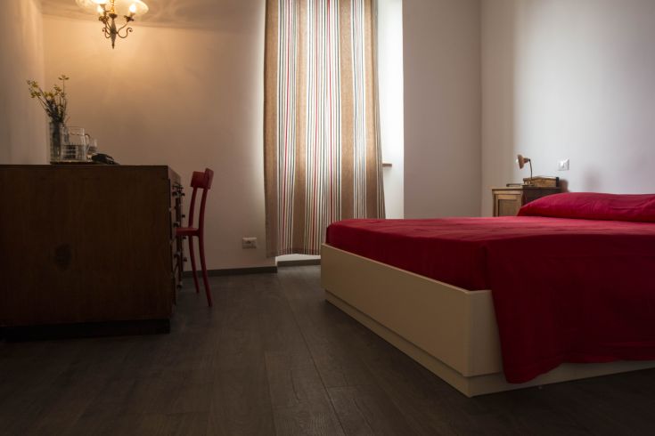 The interior of a well-lit bedroom, featuring simple and comfortable furnishings.
