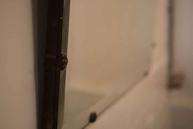 Close-up of a mirror with a metallic frame in a simple setting.