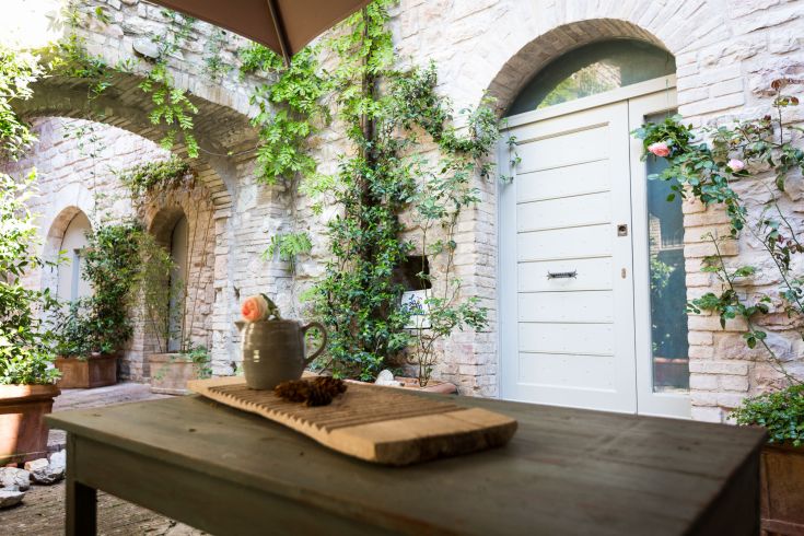 A peaceful corner with a simple table and white doors, surrounded by green plants.