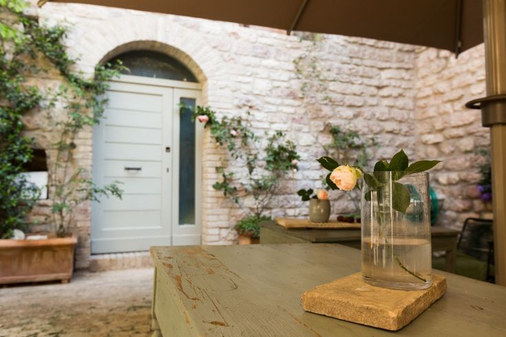 A serene corner with a rose in a glass, surrounded by the ancient walls of an Umbrian building.