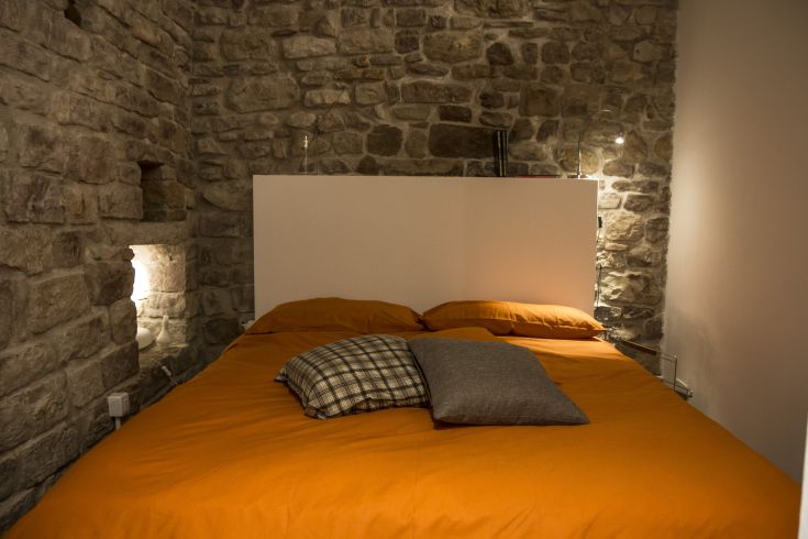 Cozy room with stone walls and orange linens, perfect for a restful stay.