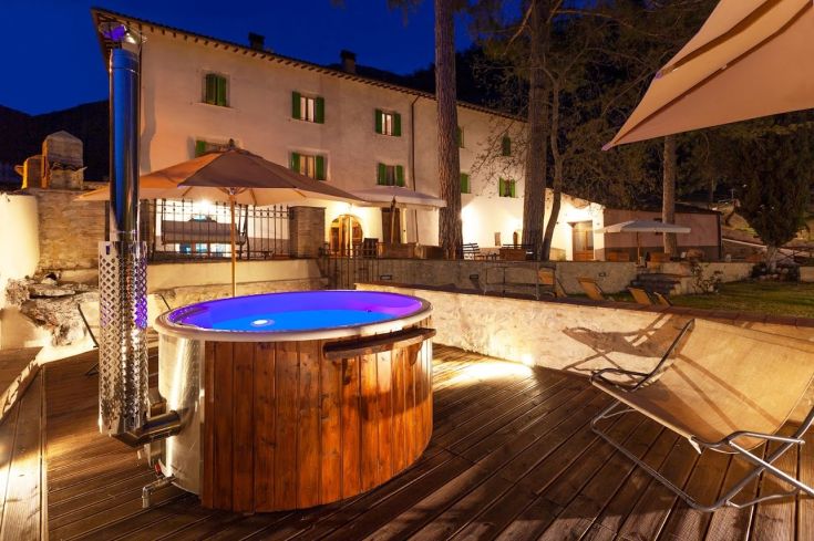 A cozy corner with a hot tub and a stunning view of the surrounding farmhouse.
