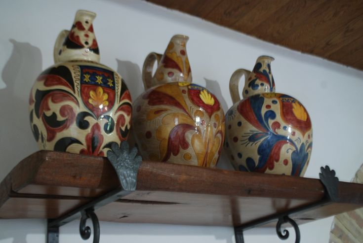 Vases en céramique colorés disposés sur une étagère en bois, avec des décorations simples.