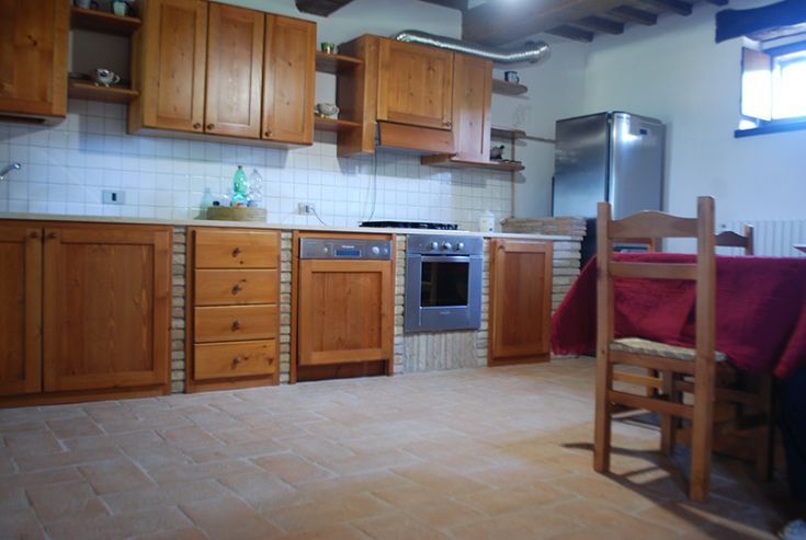 Cuisine simple et accueillante, dotée de mobilier en bois et d'un sol en terre cuite.