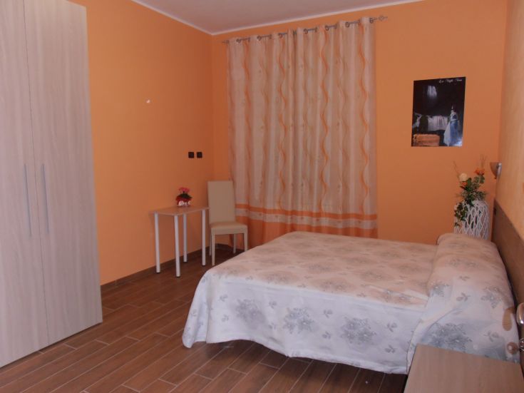 Camera semplice e confortevole in un ambiente dai toni caldi e luminosi.