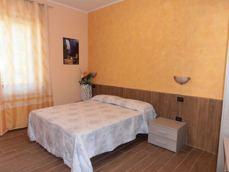 Camera semplice e luminosa con letto matrimoniale e arredo essenziale, creata per un ambiente confortevole.