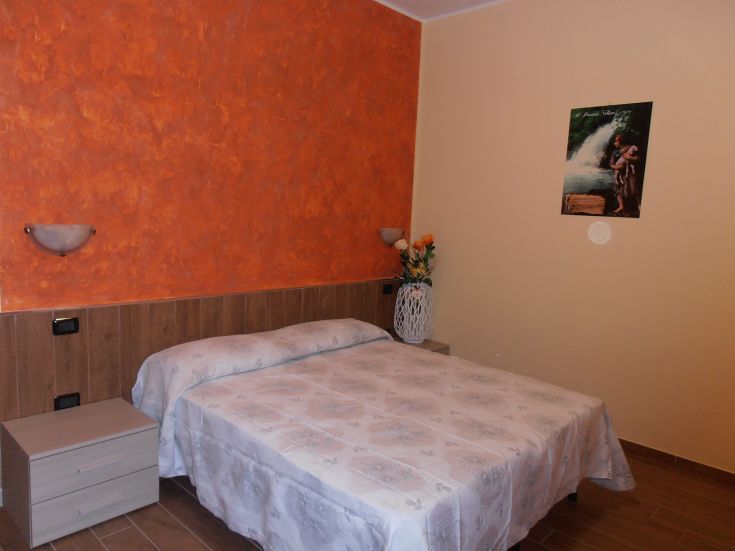 Camera confortevole con parete arancione, arredata in modo pratico e sobrio.