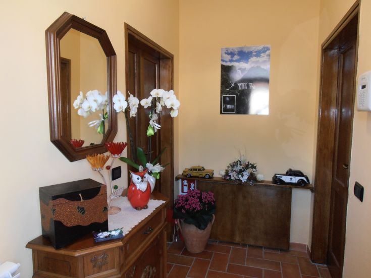 Ingresso semplice della casa, con alcune decorazioni floreali e fotografie, creando un ambiente accogliente.