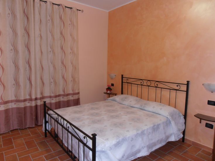 Camera semplice e accogliente con letti in ferro battuto e decorazioni sobrie. Ideale per momenti di relax.