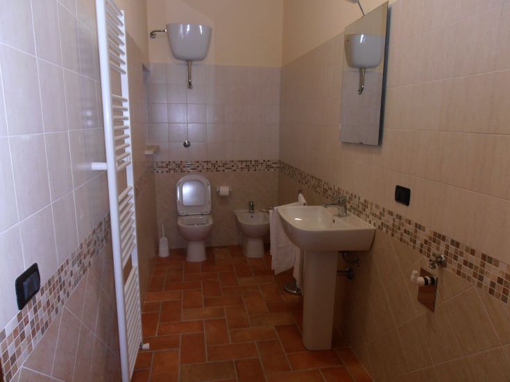 Un bagno contemporaneo con piastrelle chiare, lavabo e servizi. Ambientazione pratica e ben organizzata.