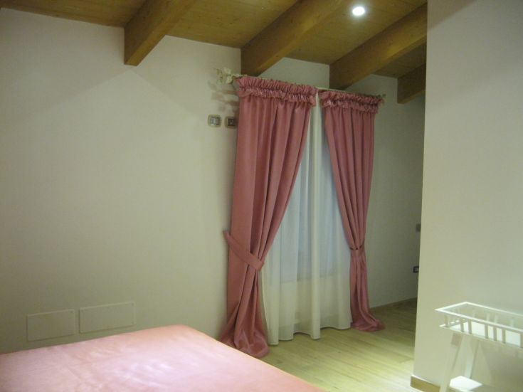 A bedroom with pink curtains and bright furnishings, perfect for a relaxing moment.