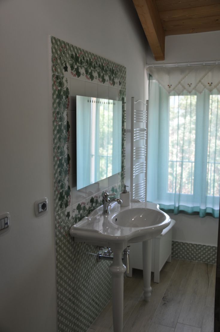 A minimalist bathroom interior featuring a sink and a window, decorated with ornate tiles.