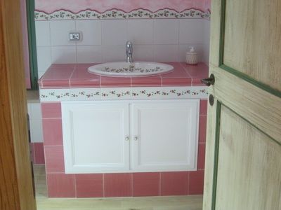 A bright bathroom interior with a sink and pink tiles.