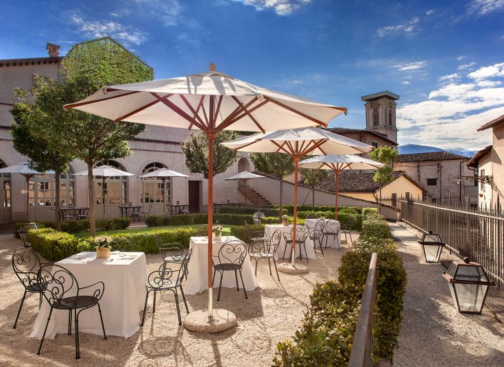 A well-kept garden with tables and umbrellas, perfect for outdoor lunches.