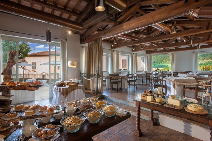 A simple dining room with a buffet of sweets, cheeses, and traditional dishes in a natural setting.