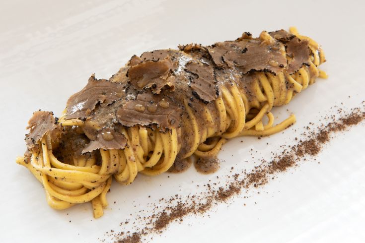 Fettuccine with truffles served on a plate, garnished with slices of black truffle.