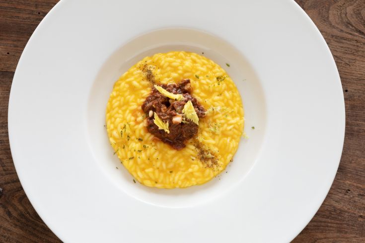 Yellow risotto served with meat, a simple and beloved dish.