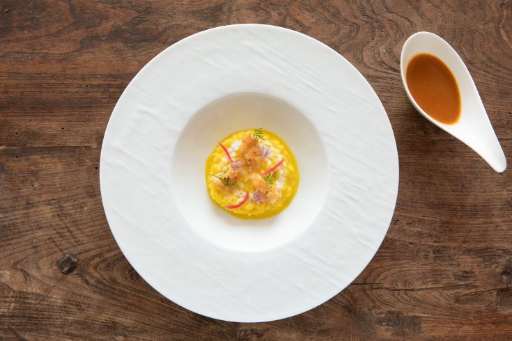 A fresh risotto dish made with seasonal ingredients, served with a sauce to add as desired.