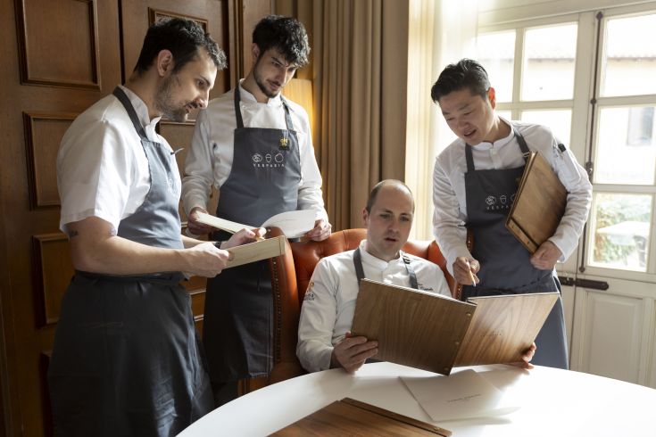 Four chefs discussing menus in a well-organized and collaborative kitchen environment.