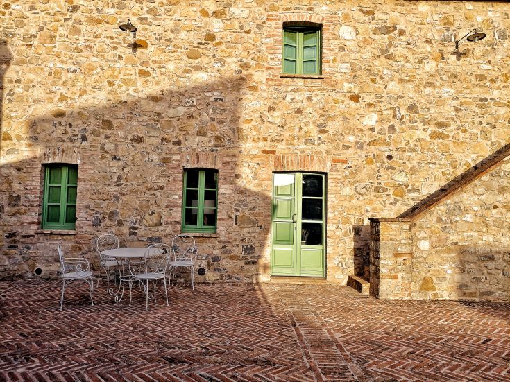 Historic stone facade with green windows and an accessible patio.