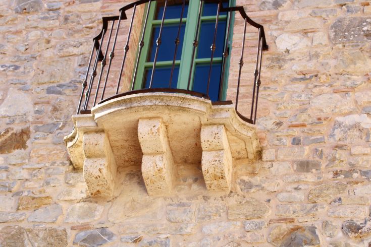 A balcony with decorations on a stone wall, typical of an Umbrian village.