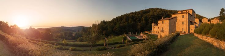 A peaceful medieval village surrounded by greenery, featuring a pool and a restaurant overlooking the landscape.