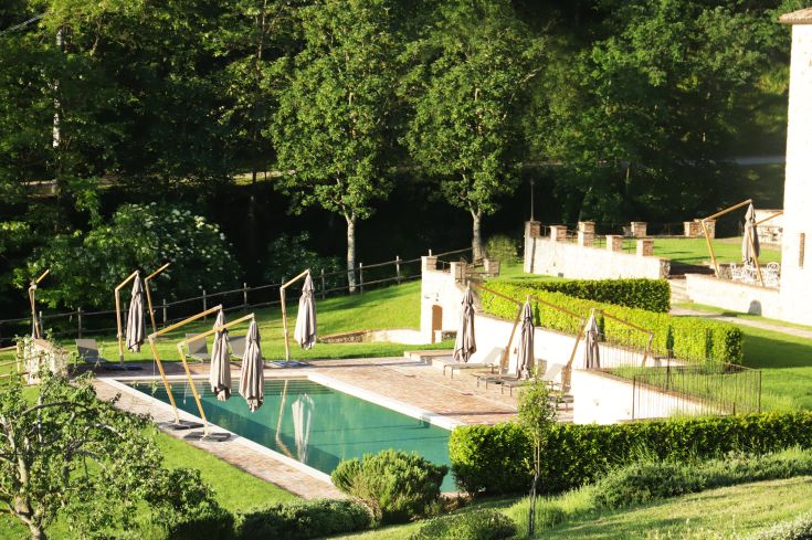 An image showing a pool surrounded by greenery in a medieval village setting.