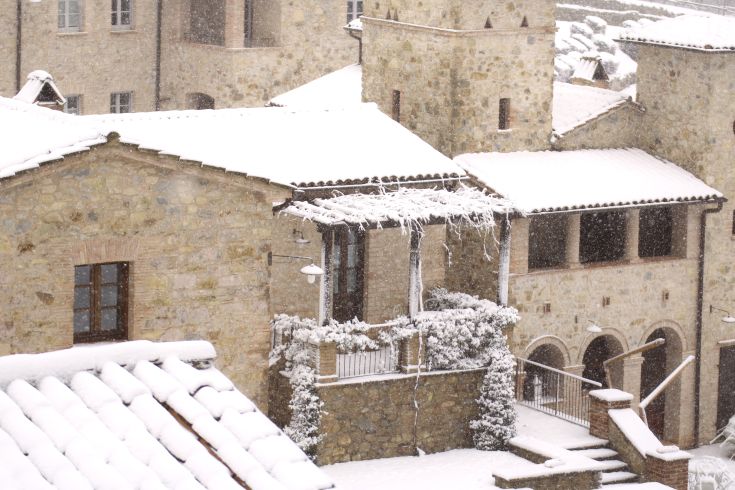 A snowy medieval village area featuring stone buildings and snow-covered rooftops.