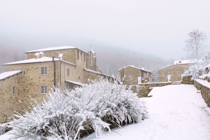 A medieval village covered in snow, featuring stone streets and historic buildings, creating a serene atmosphere.